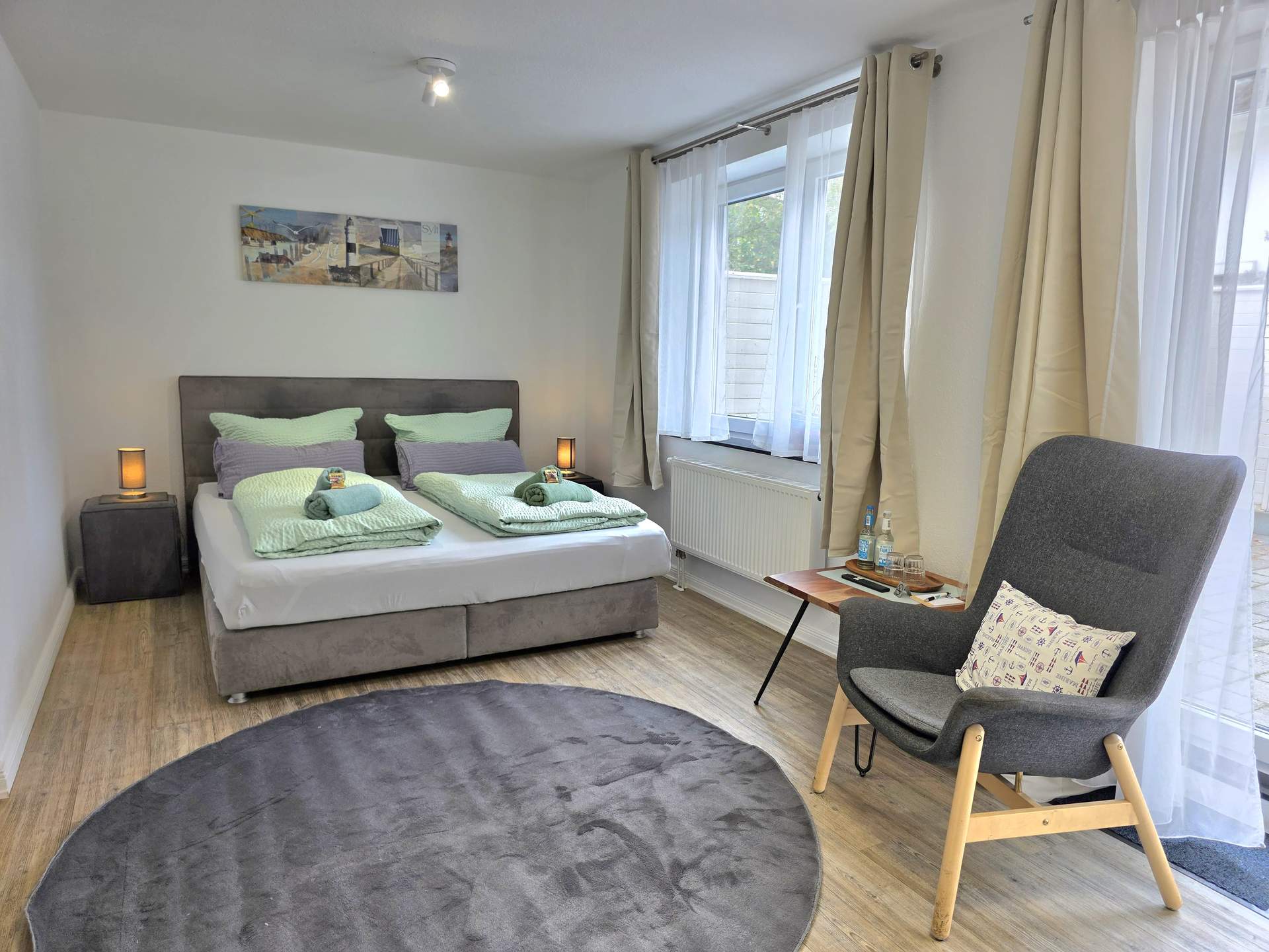 Doppelbett mit Sessel im Zimmer Backbord der Pension ElbKate in Glückstadt