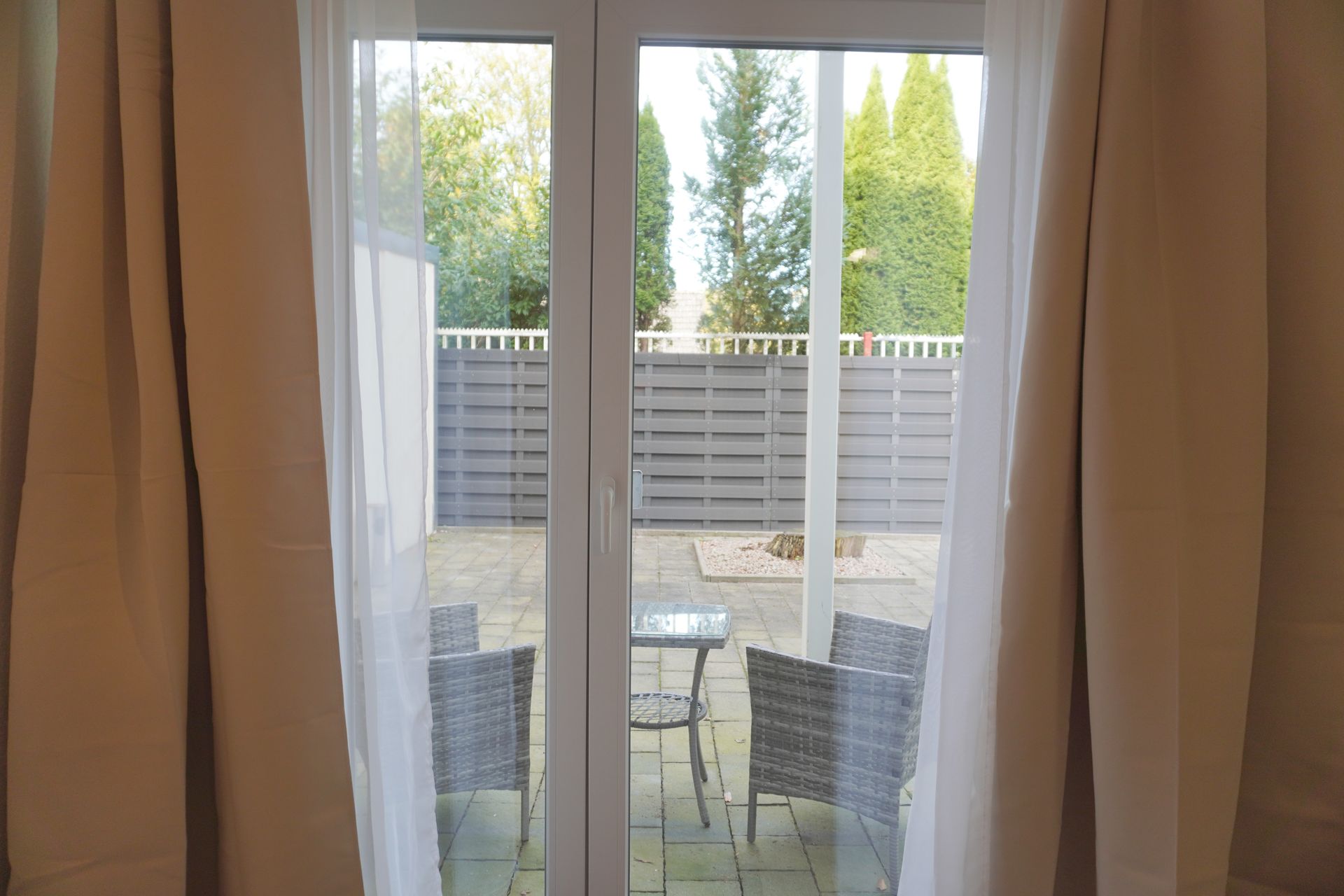 Blick durch die Terrassentür auf die Terrasse mit Sitzgruppe an den Zimmern im Erdgeschoss der Pension ElbKate in Glückstadt